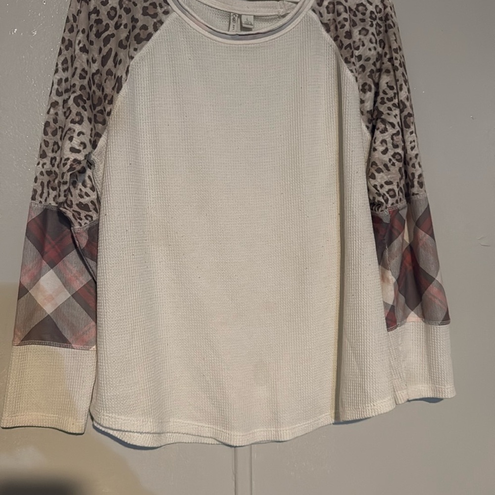 A white shirt with cheetah print and plaid sleeves